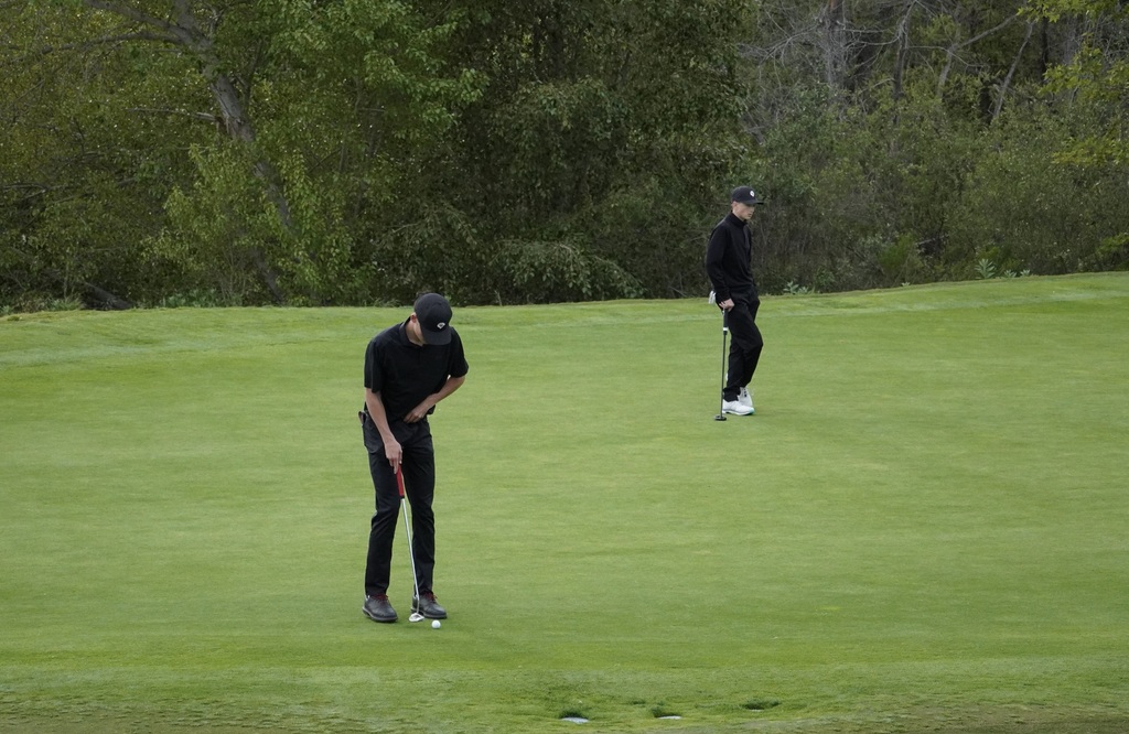 Hunter putting on the green of hole 3 while Jase watches on.