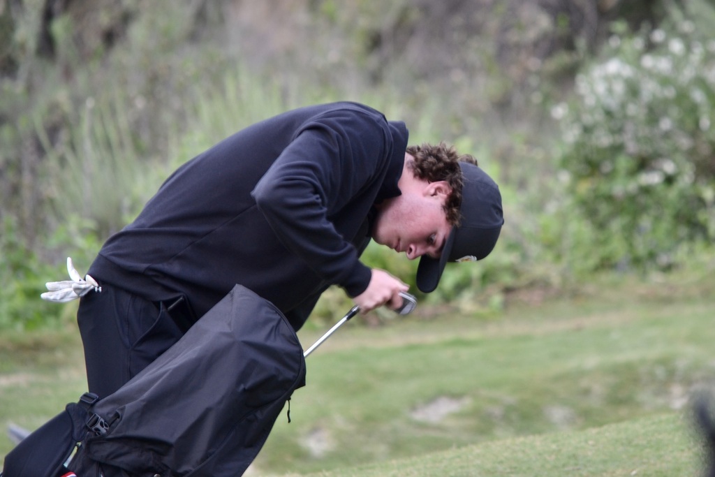 Jacob is protecting his clubs in the rain that hit halfway through the match.