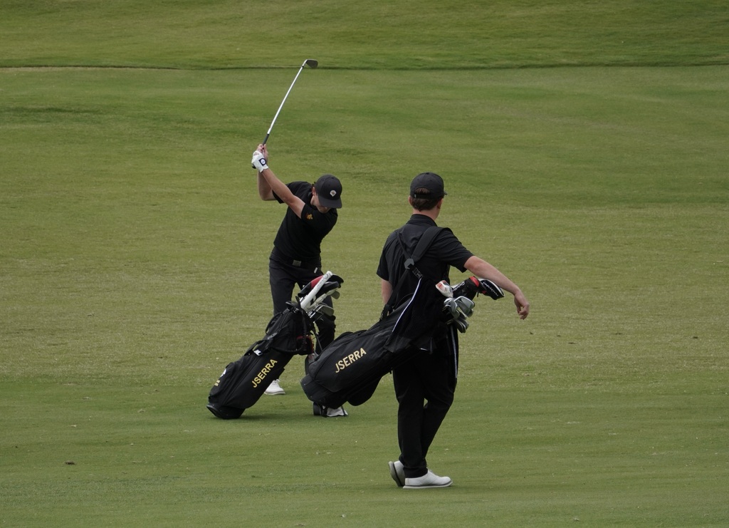 Adam with his approach shot into the green of hole 2 while teammate Liam McNamara watches on.