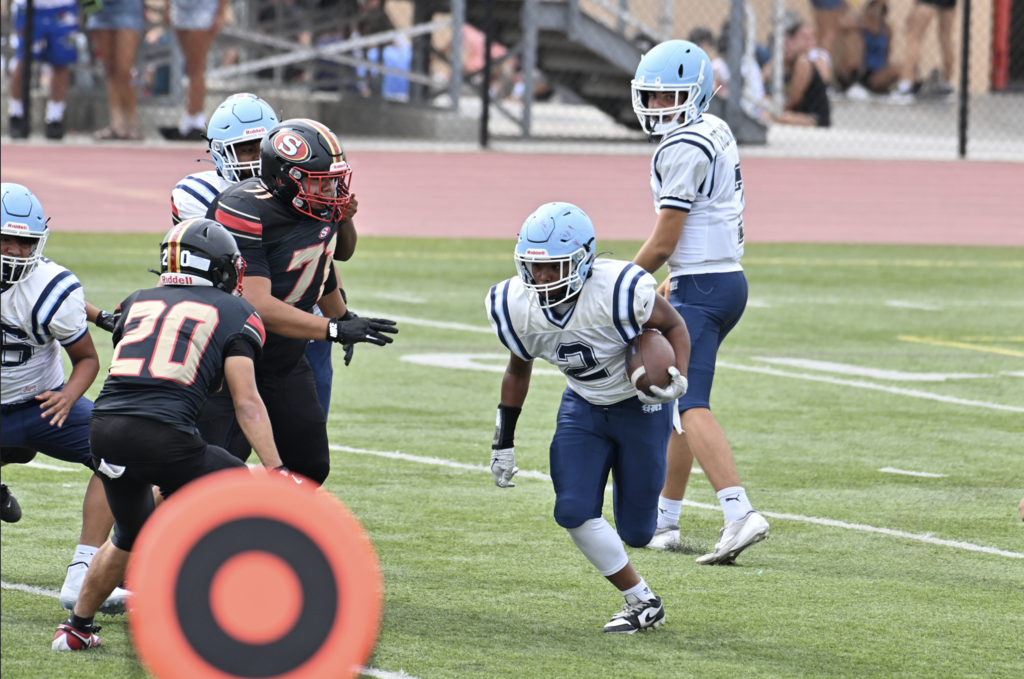 Henry DeAssis gets the carry out of the backfield for the JV Trojans