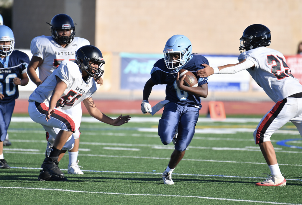 Trojans Frosh team running back Noah Thomas splits the Knights defenders.  For more great photos of the season, visit:  https://unifootballboosters.smugmug.com/20252026-UNI-TROJANS-FOOTBALL/2025FROSH